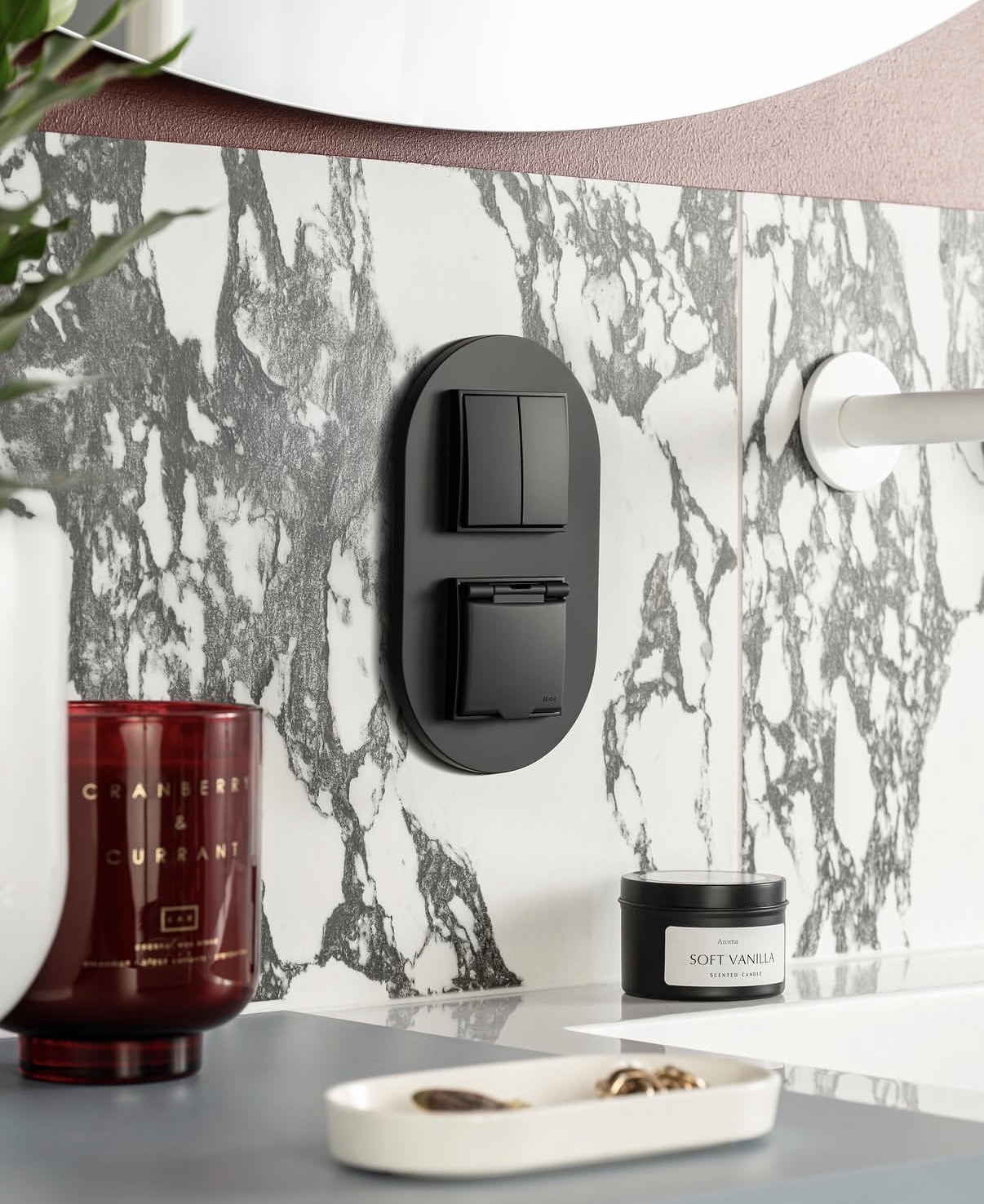 Matte black oval switch and socket combo against grey marble tile